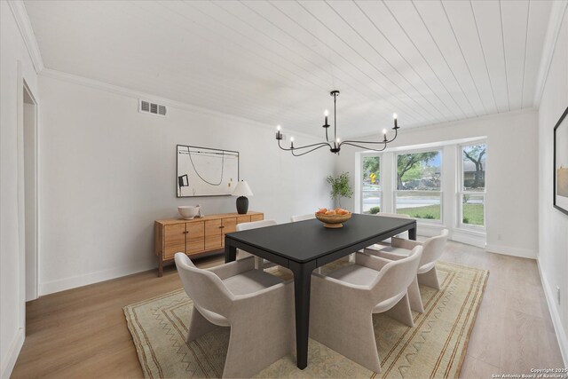 dining area featuring visible vents, baseboards, an inviting chandelier, ornamental molding, and light wood finished floors