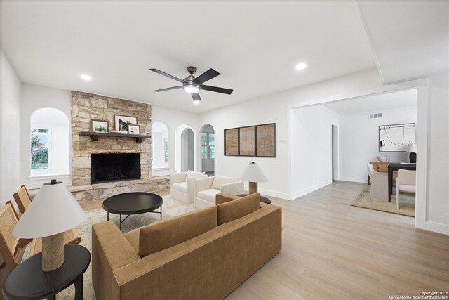 living area featuring a fireplace, visible vents, light wood-type flooring, and a healthy amount of sunlight