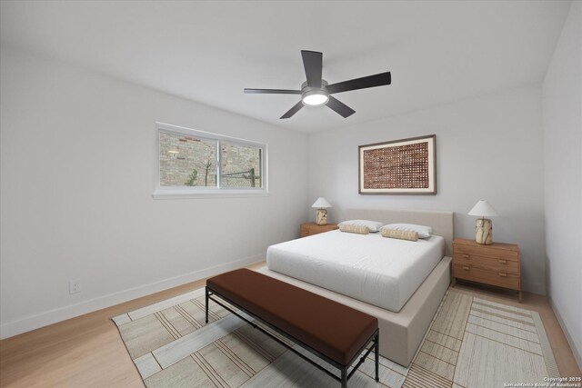 bedroom featuring ceiling fan, light wood-style floors, and baseboards