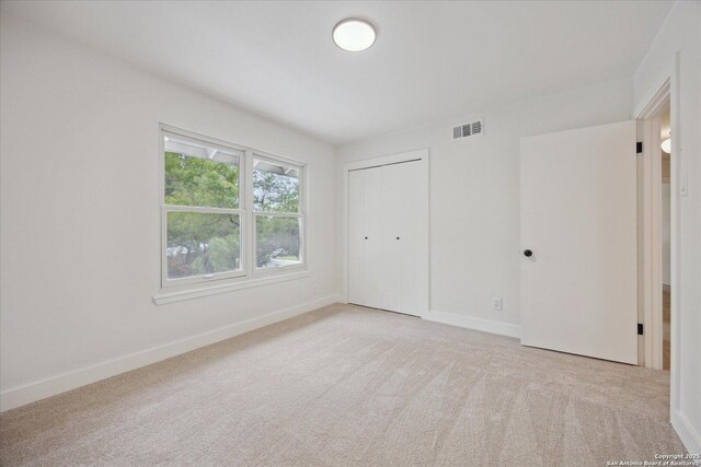unfurnished bedroom featuring a closet, visible vents, carpet, and baseboards