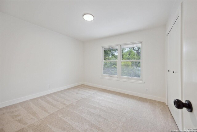 unfurnished bedroom featuring light colored carpet and baseboards