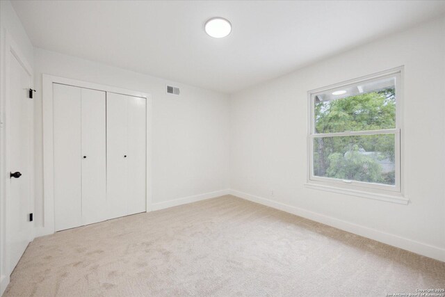 unfurnished bedroom featuring carpet flooring, a closet, visible vents, and baseboards