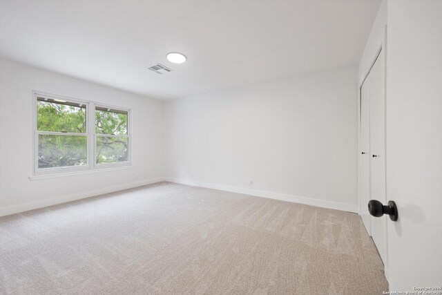 empty room with light colored carpet, visible vents, and baseboards