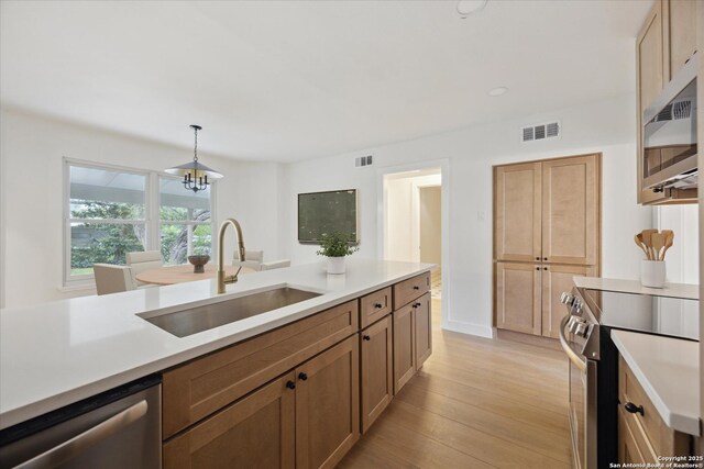 kitchen with a sink, appliances with stainless steel finishes, visible vents, light countertops, and light wood finished floors