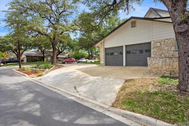 view of property exterior with a garage, concrete driveway, and stone siding