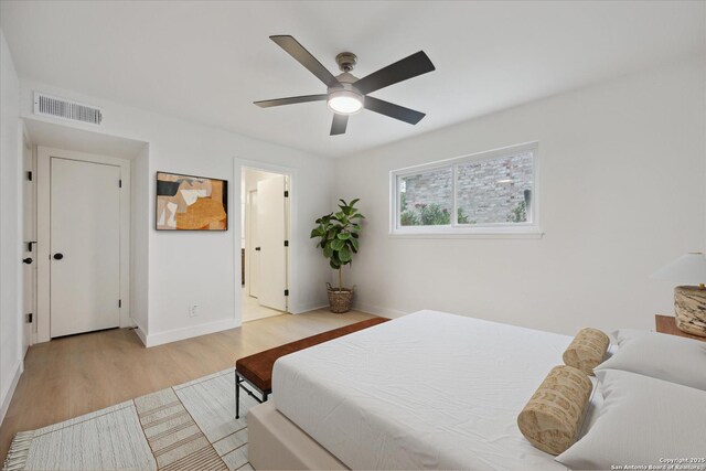 bedroom with a ceiling fan, visible vents, wood finished floors, and baseboards