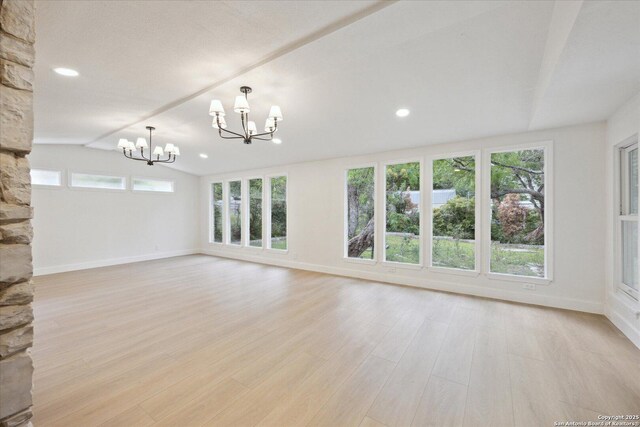 unfurnished living room with plenty of natural light, a chandelier, and baseboards