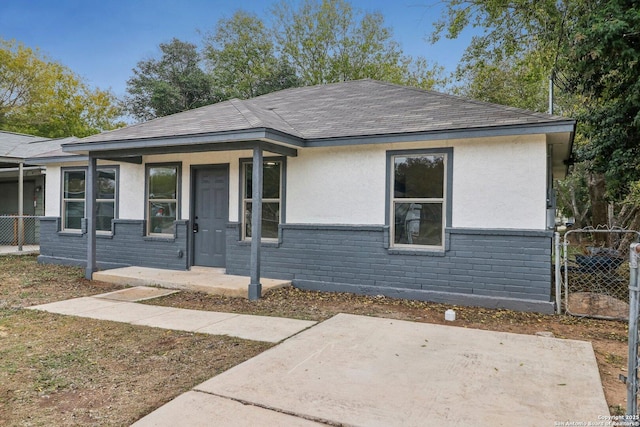 view of front of house featuring fence, roof with shingles, and stucco siding