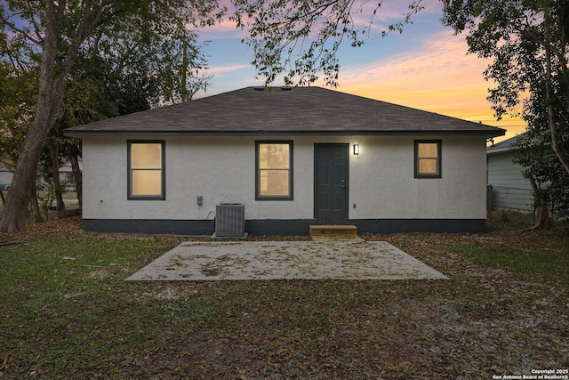 back of property at dusk featuring stucco siding, cooling unit, and a patio
