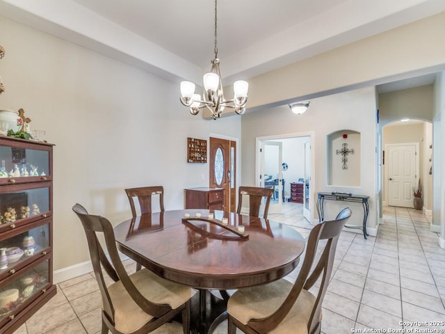 dining space featuring light tile patterned floors, a chandelier, baseboards, and arched walkways