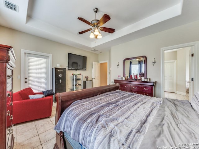 bedroom with light tile patterned flooring, a raised ceiling, and multiple windows