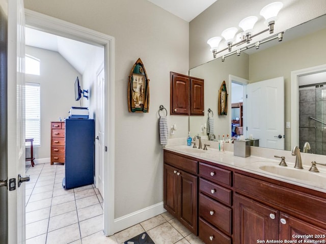 bathroom featuring a sink, double vanity, baseboards, tile patterned floors, and tiled shower