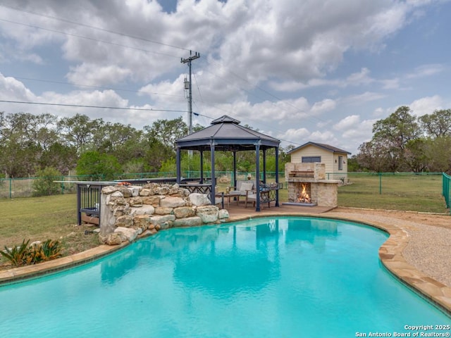 pool with an outdoor stone fireplace, a gazebo, a patio area, fence, and a yard