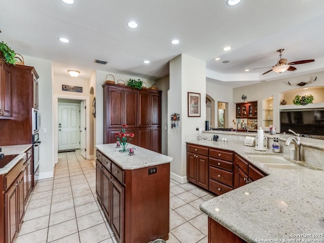 kitchen with light tile patterned floors, a sink, visible vents, ceiling fan, and a center island