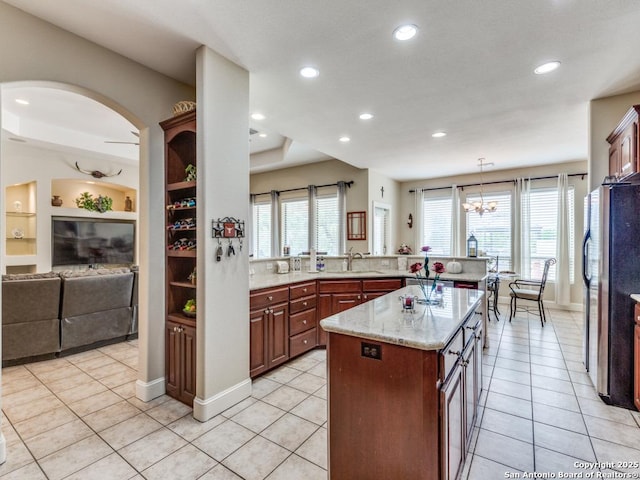 kitchen with recessed lighting, freestanding refrigerator, light stone counters, light tile patterned floors, and a sink