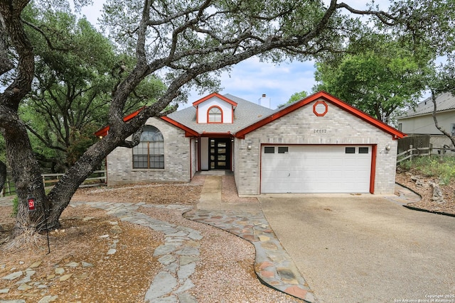 view of front of house with driveway, roof with shingles, brick siding, and a garage