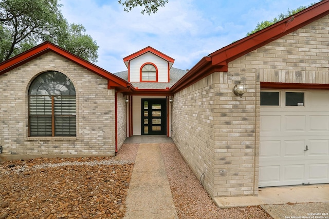 doorway to property featuring roof with shingles, brick siding, and an attached garage