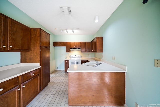 kitchen featuring a textured ceiling, a sink, light countertops, under cabinet range hood, and white electric stove