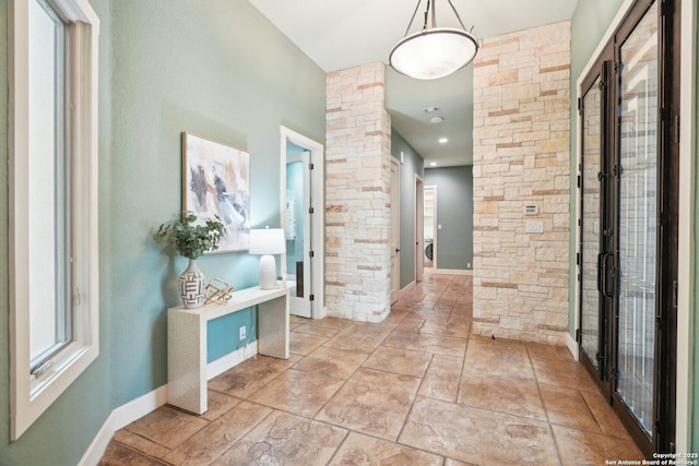 hall featuring baseboards and decorative columns