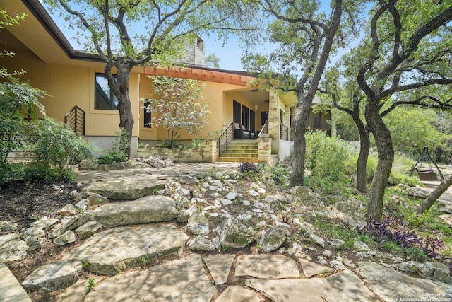 exterior space featuring stucco siding, a chimney, and a porch