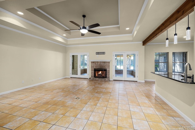 unfurnished living room featuring light tile patterned floors, ceiling fan, french doors, crown molding, and a tray ceiling