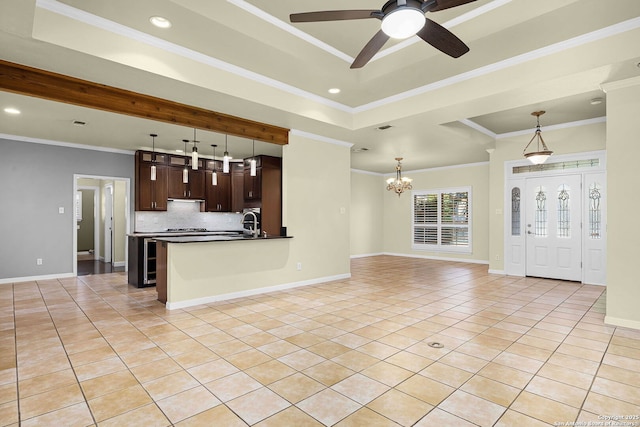 kitchen featuring light tile patterned floors, dark countertops, dark brown cabinets, open floor plan, and ceiling fan with notable chandelier