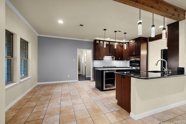 kitchen featuring light tile patterned floors, crown molding, a sink, visible vents, and dark brown cabinetry