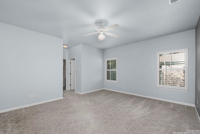 empty room featuring baseboards, a ceiling fan, and light colored carpet