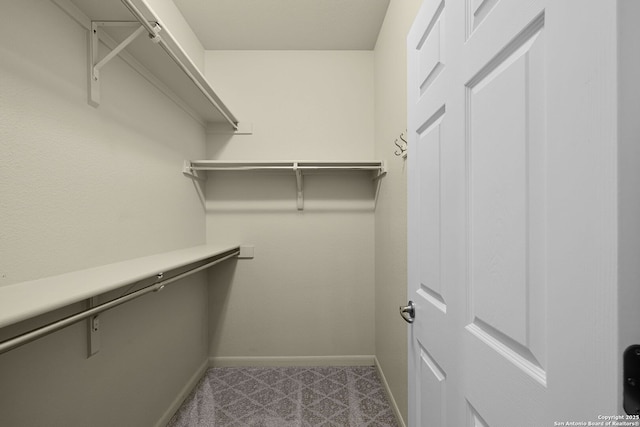 spacious closet featuring dark colored carpet