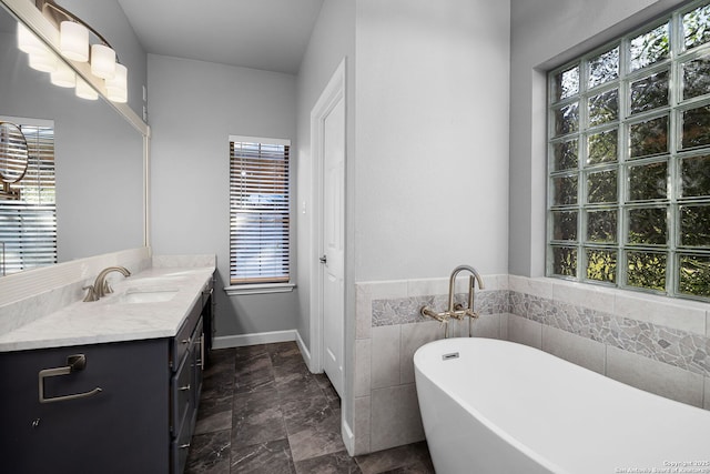 full bathroom featuring a soaking tub, vanity, and plenty of natural light