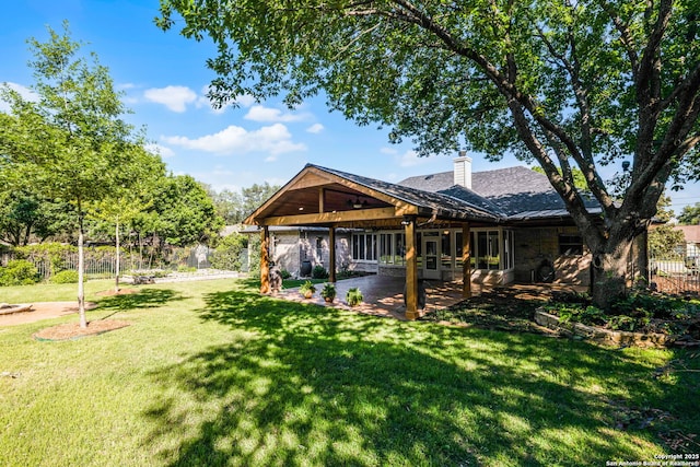 back of property featuring a chimney, a yard, a standing seam roof, fence, and a patio