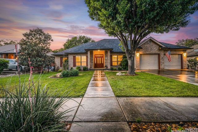 view of front of home featuring a garage, driveway, a yard, and roof with shingles