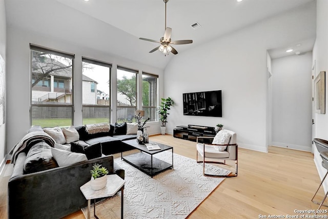 living room featuring a ceiling fan, visible vents, baseboards, and light wood-style floors