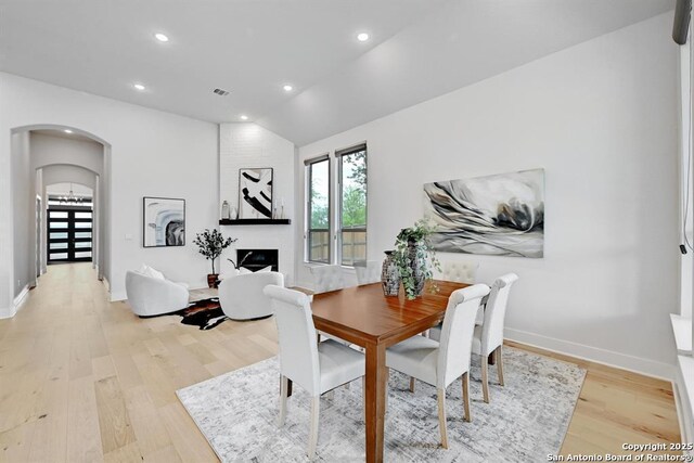 dining room with baseboards, recessed lighting, arched walkways, and light wood-style floors