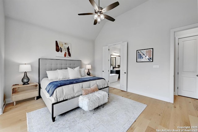 bedroom featuring light wood-style floors, high vaulted ceiling, ceiling fan, ensuite bath, and baseboards