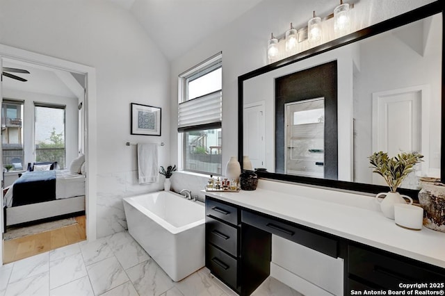 full bath featuring connected bathroom, a wainscoted wall, marble finish floor, a freestanding bath, and lofted ceiling