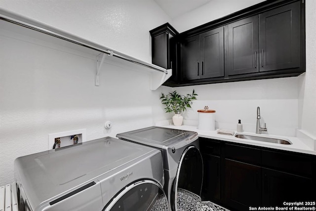 clothes washing area with separate washer and dryer, cabinet space, and a sink