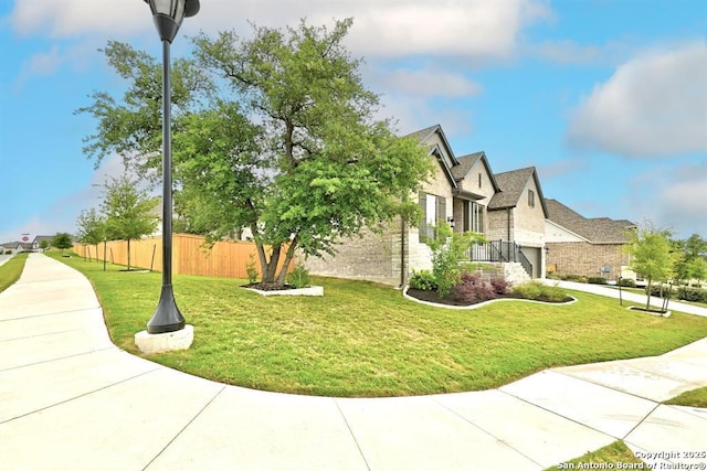 view of side of home featuring brick siding, a yard, and fence