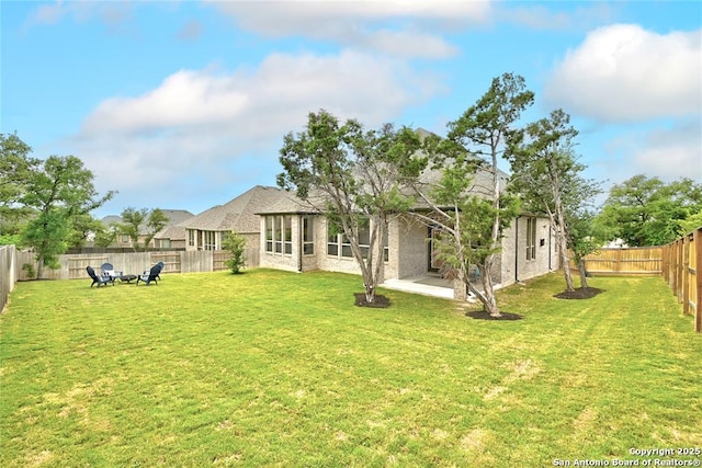 back of property featuring a lawn, a fenced backyard, and a patio area