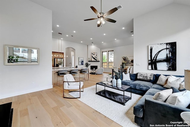 living area with visible vents, arched walkways, recessed lighting, light wood finished floors, and a ceiling fan