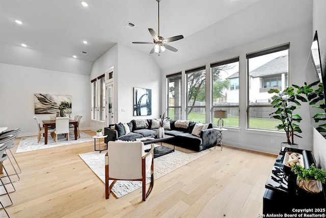 living room featuring visible vents, a ceiling fan, light wood finished floors, and vaulted ceiling