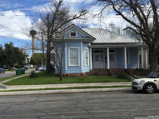 view of front of property with a porch, a front lawn, and metal roof