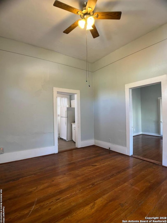empty room with hardwood / wood-style floors, a ceiling fan, and baseboards
