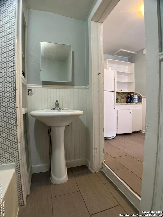 bathroom with a wainscoted wall, wood tiled floor, and a sink