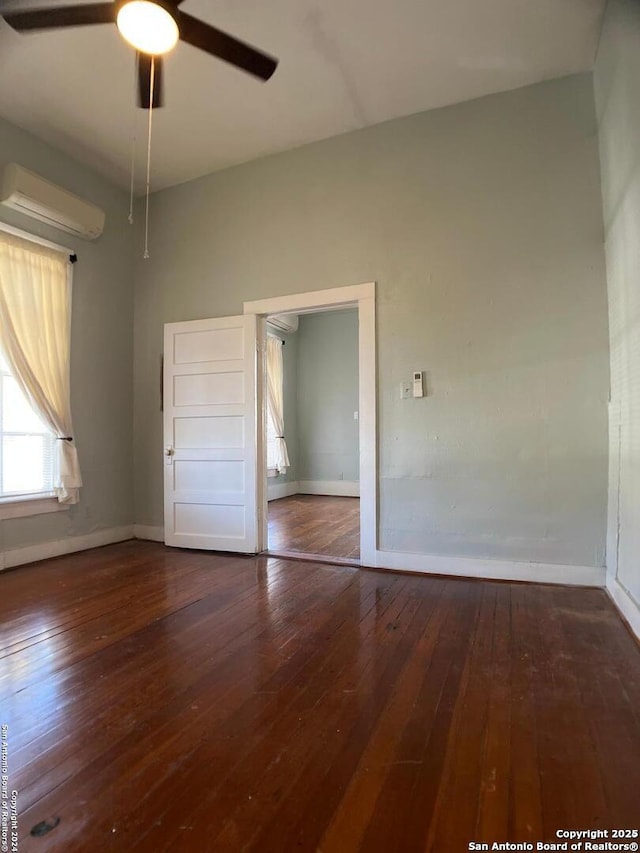 unfurnished bedroom featuring hardwood / wood-style floors, baseboards, ceiling fan, and a wall mounted AC
