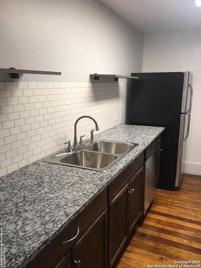 kitchen featuring a sink, dark wood-type flooring, backsplash, dishwasher, and dark brown cabinets