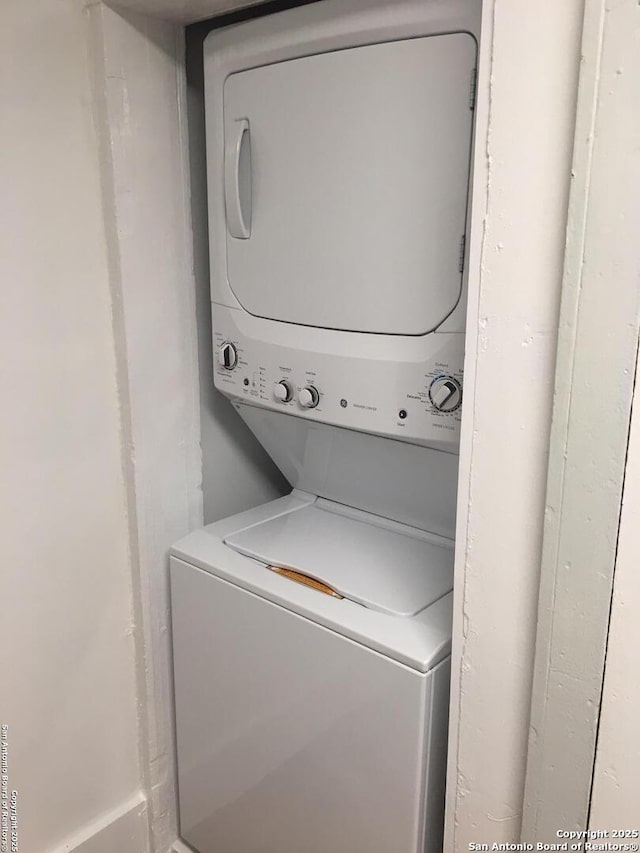 clothes washing area featuring stacked washer and dryer and laundry area
