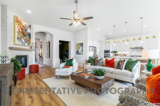 living area featuring light wood-style floors, baseboards, arched walkways, recessed lighting, and a ceiling fan