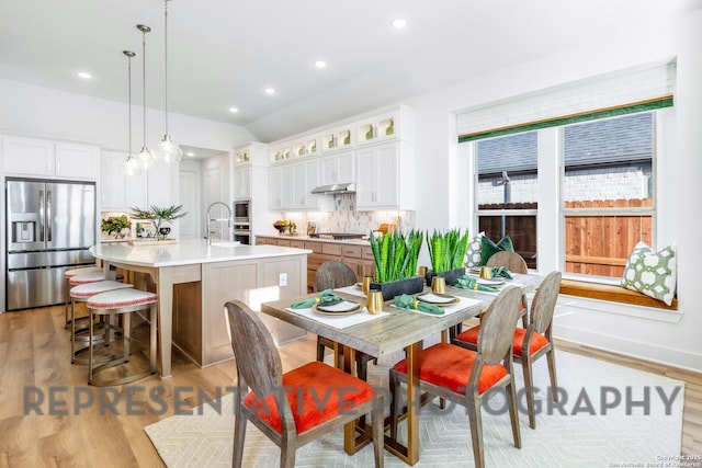 dining space featuring baseboards, recessed lighting, lofted ceiling, and light wood-style flooring