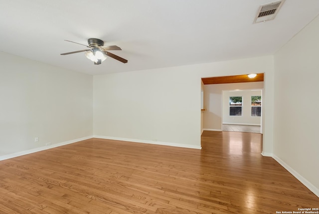empty room with baseboards, visible vents, a ceiling fan, and light wood-style flooring
